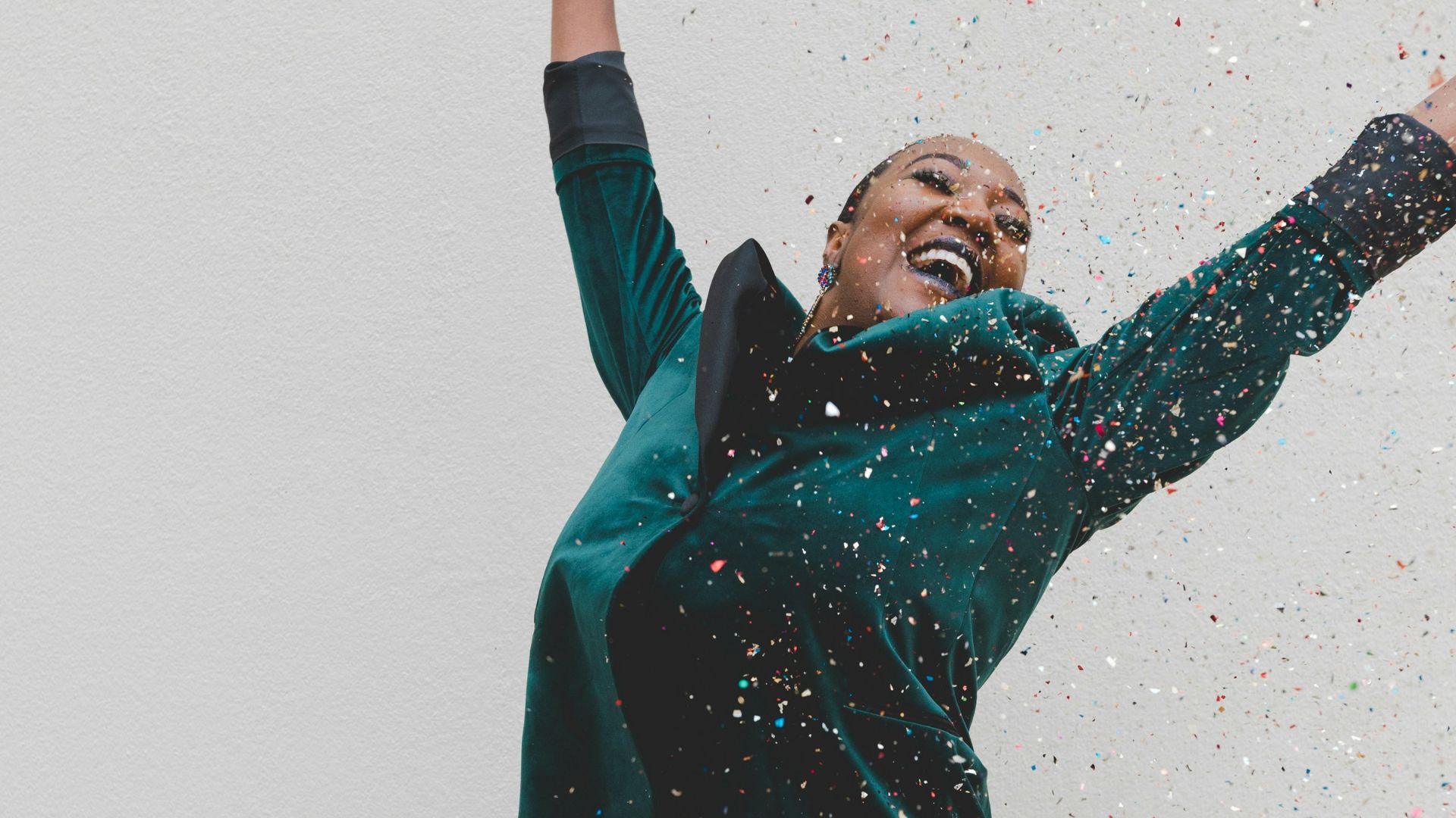 woman in green jacket raising her hands