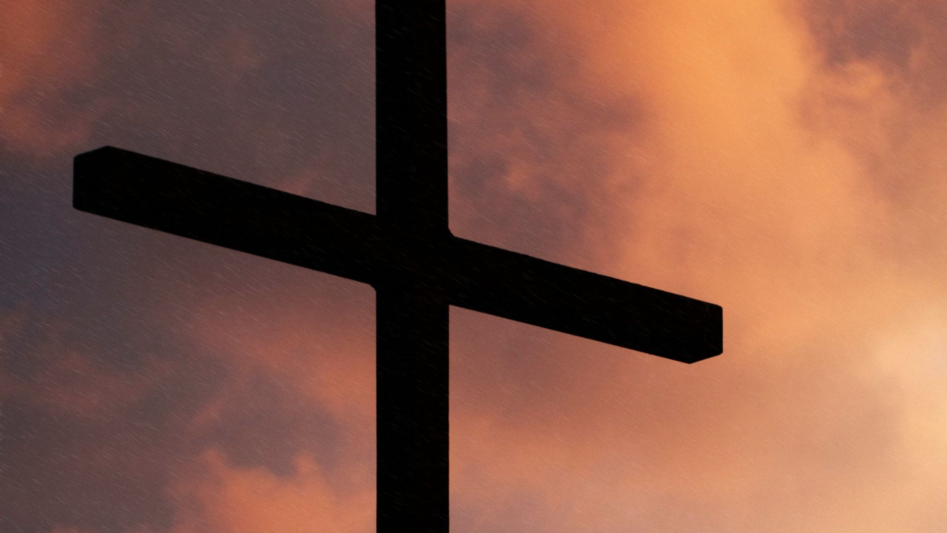 silhouette of large cross under orange sky