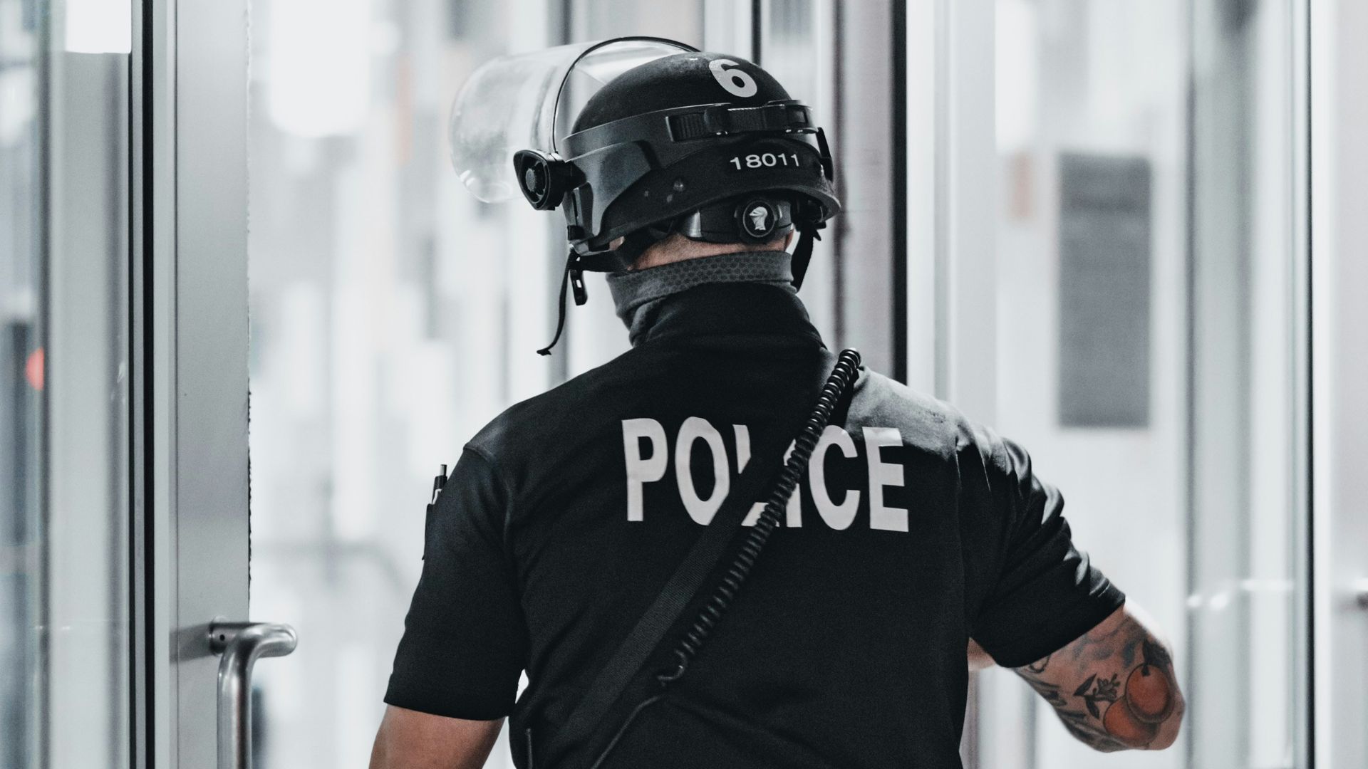 man in black helmet and black helmet standing near glass window