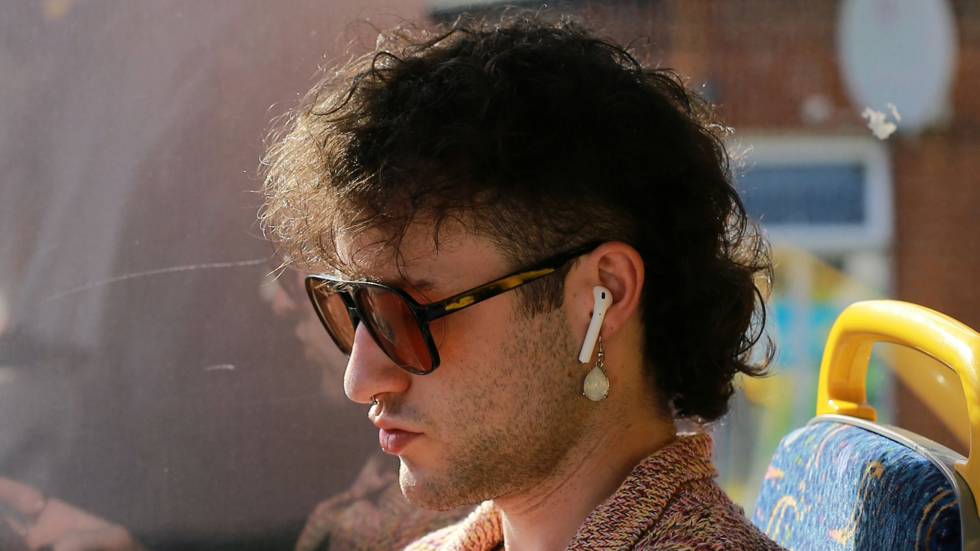 Man with sunglasses looking at phone on bus