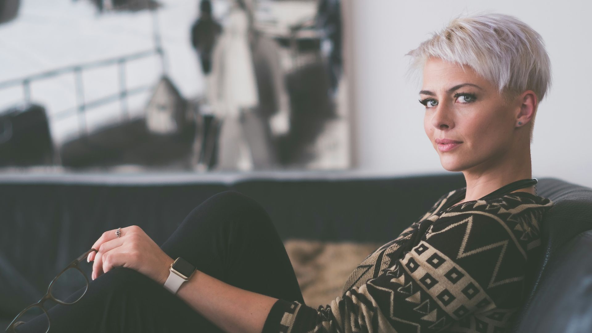 woman sitting on sofa holding eyeglasses