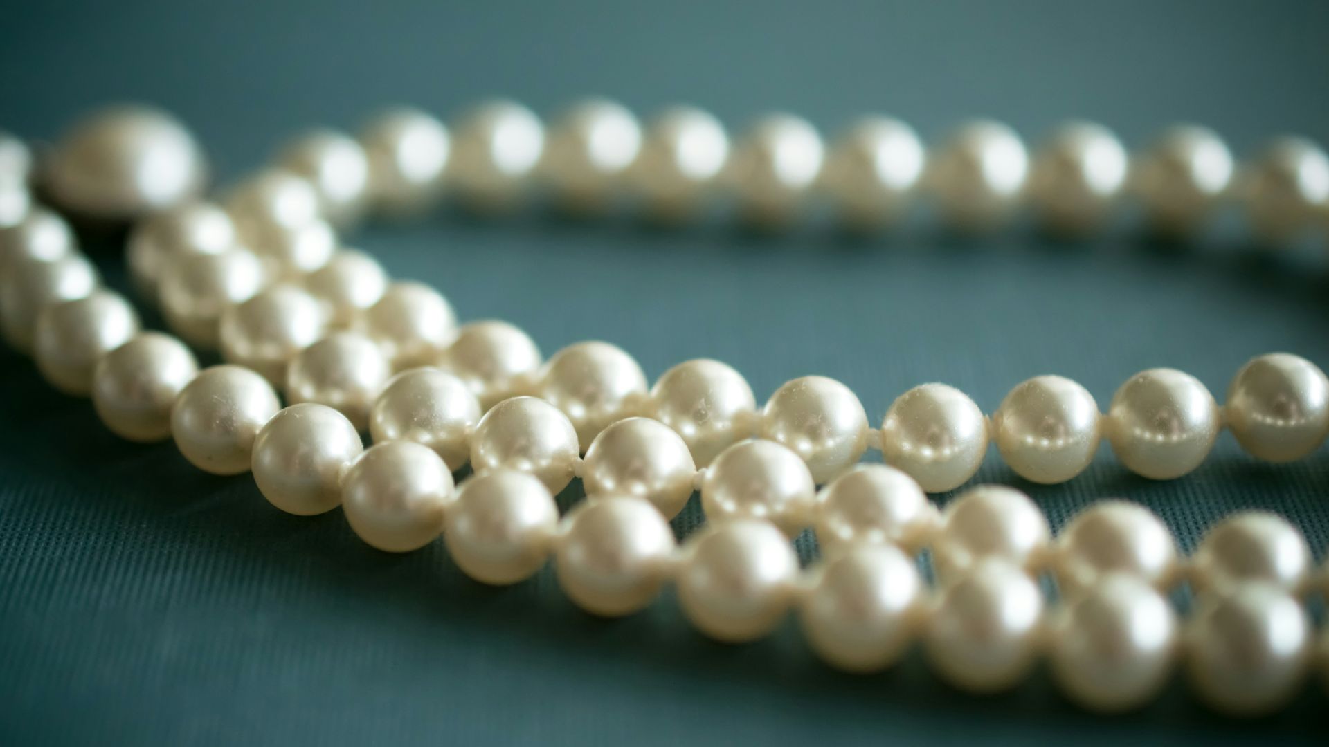 white pearl necklace on gray textile