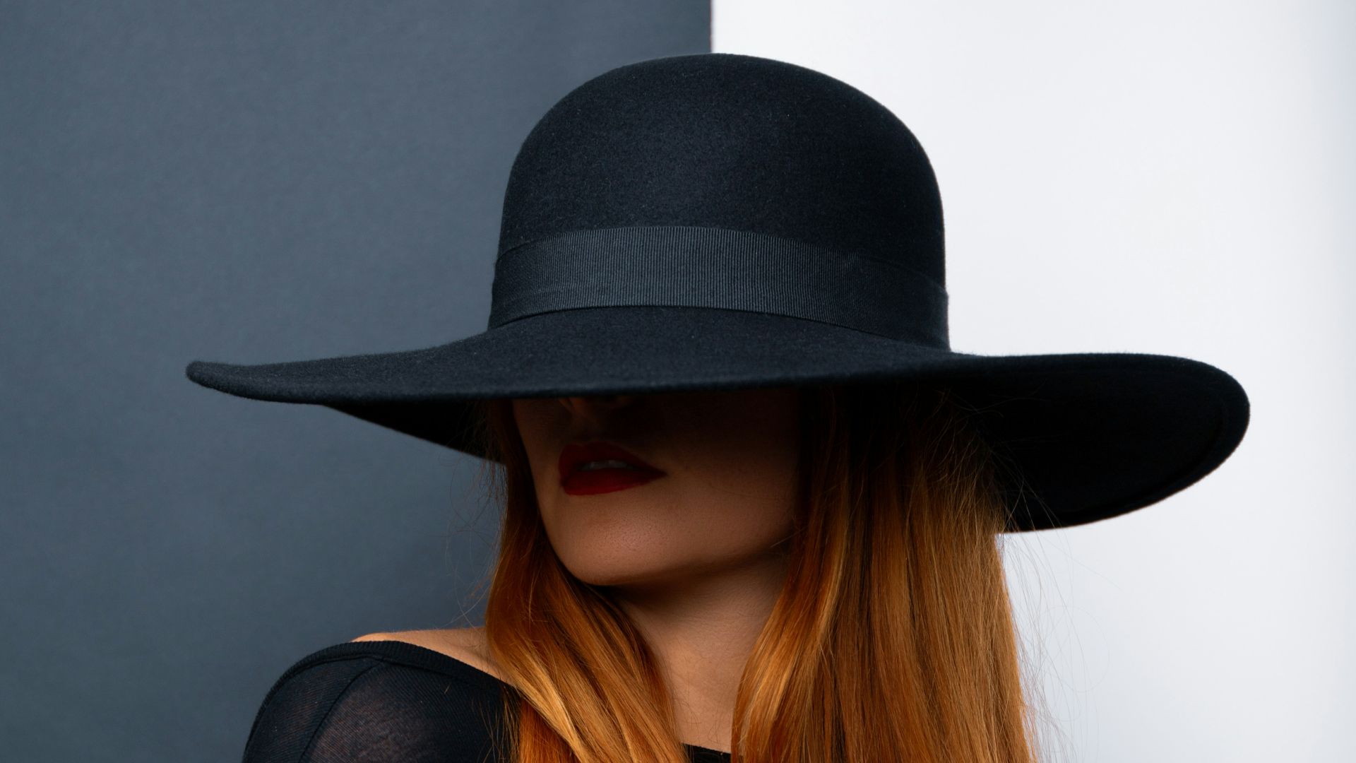 a woman with long red hair wearing a black hat