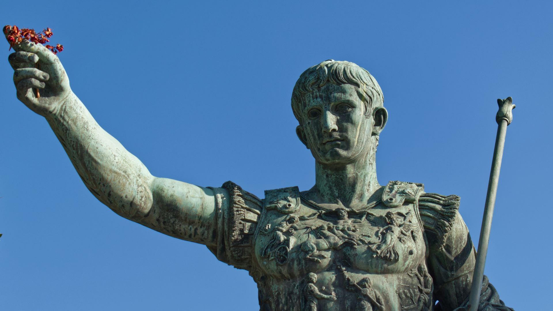 man holding stick statue under blue sky during daytime