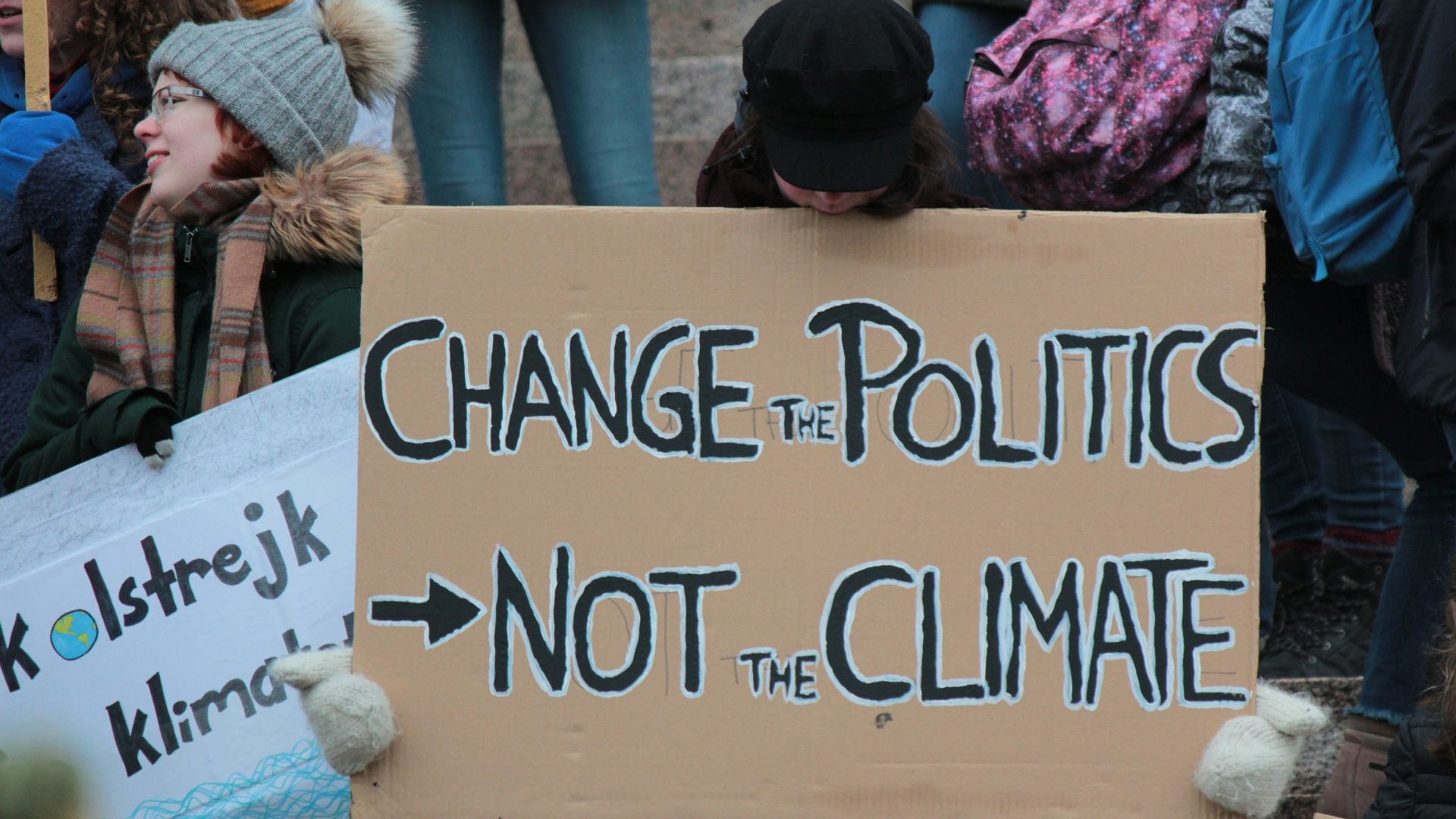 person holding change the politics not the climate printed board