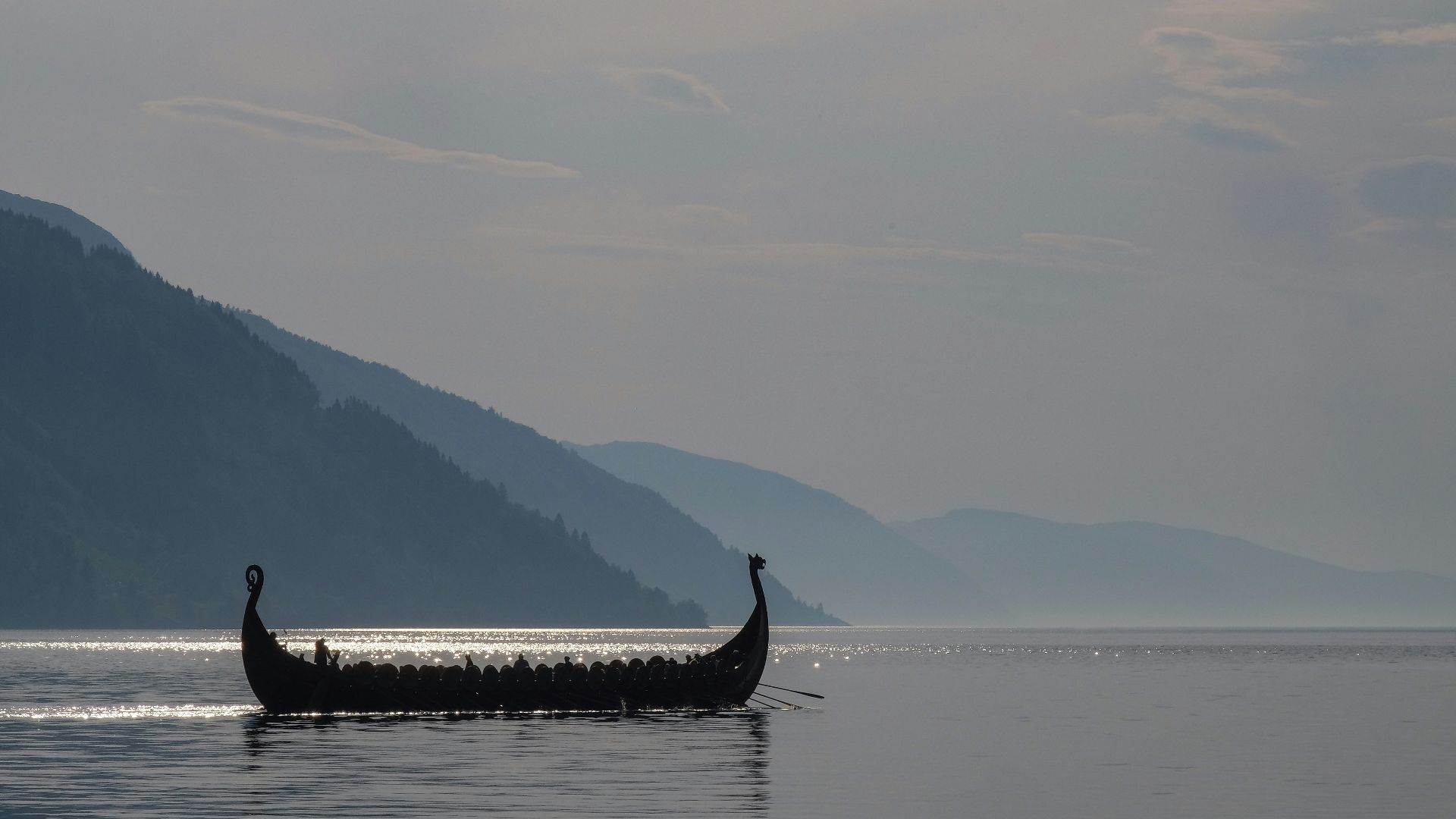 a long boat with two people in it on a lake