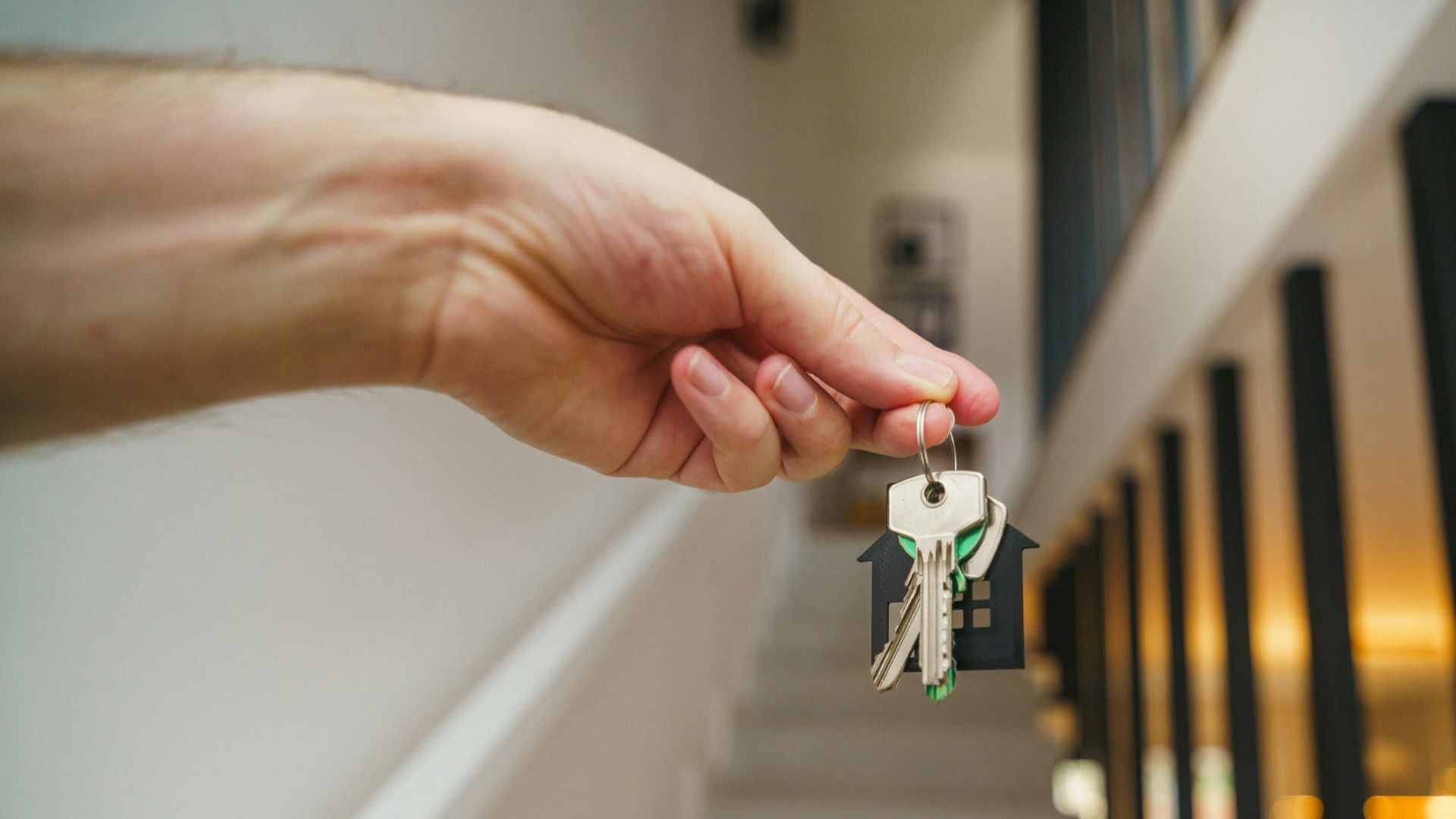 Here's a possible caption: keys being held in front of a staircase.
