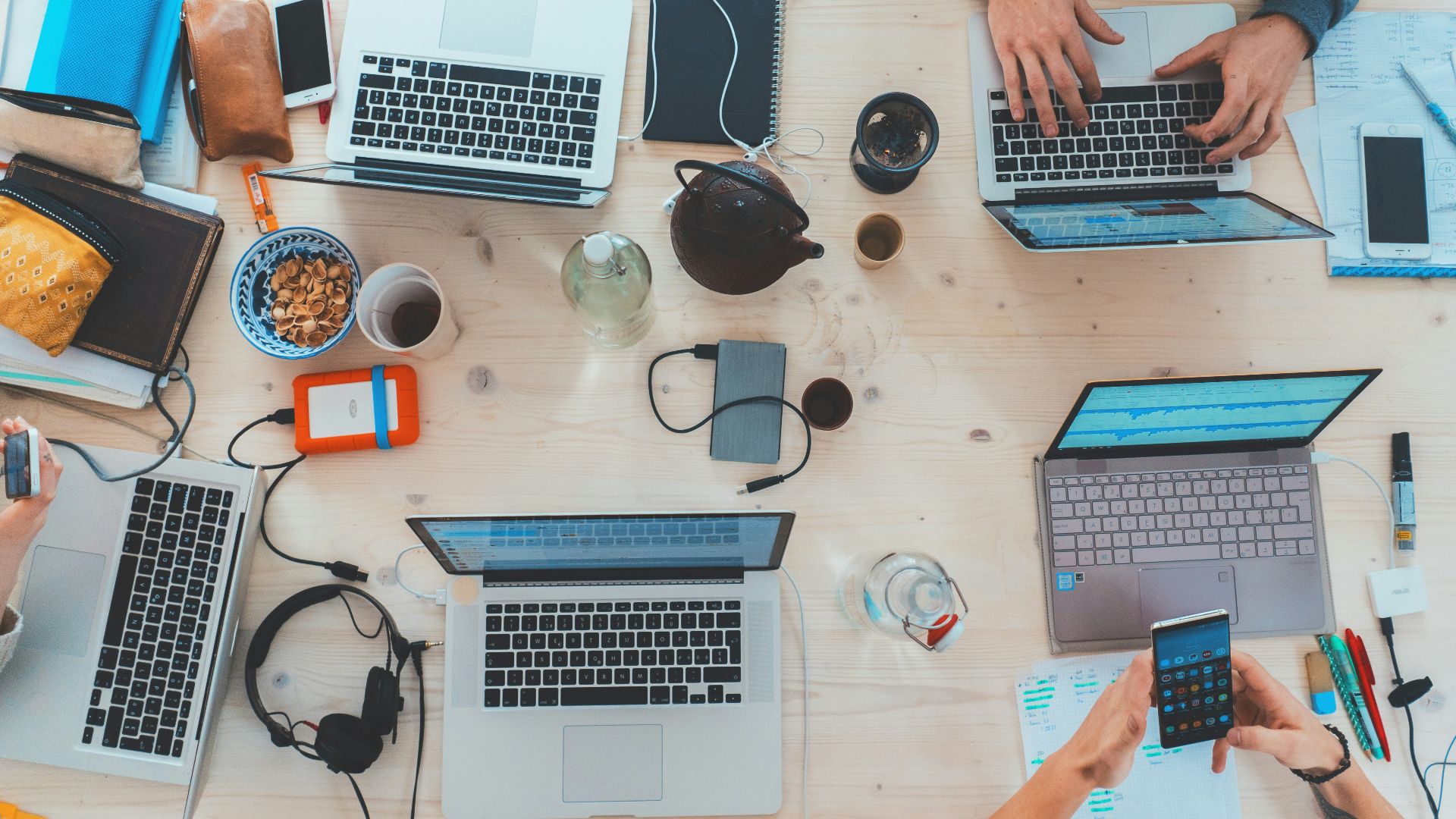 people sitting down near table with assorted laptop computers