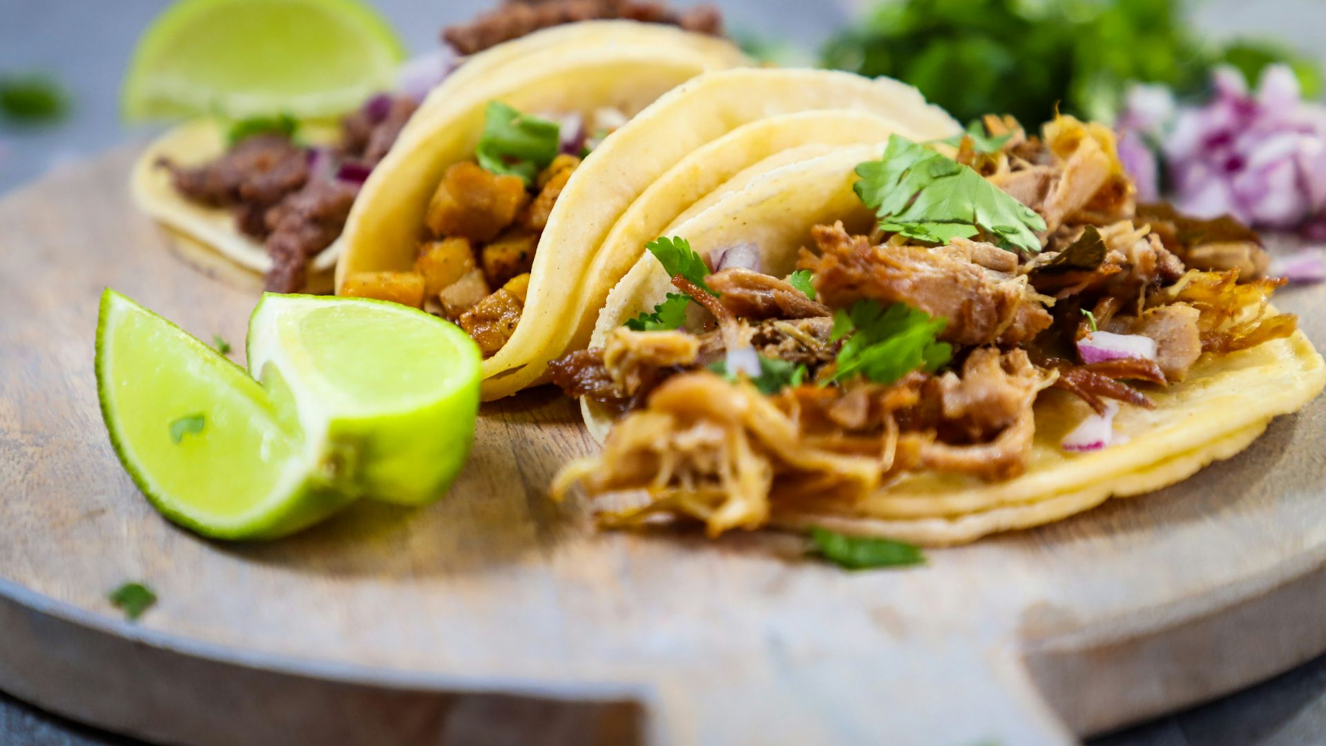a wooden plate topped with three tacos and a lime