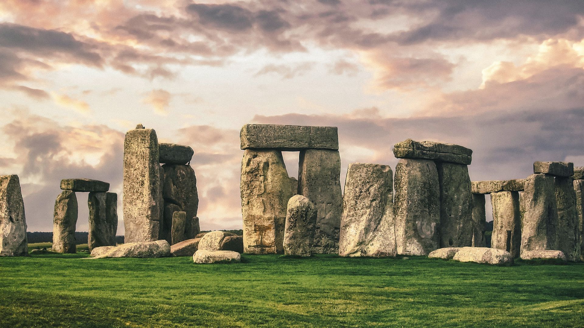 gray rock formation on green grass field under gray cloudy sky