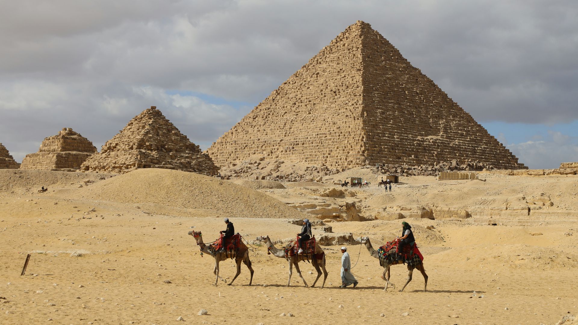 a group of people riding on the backs of camels