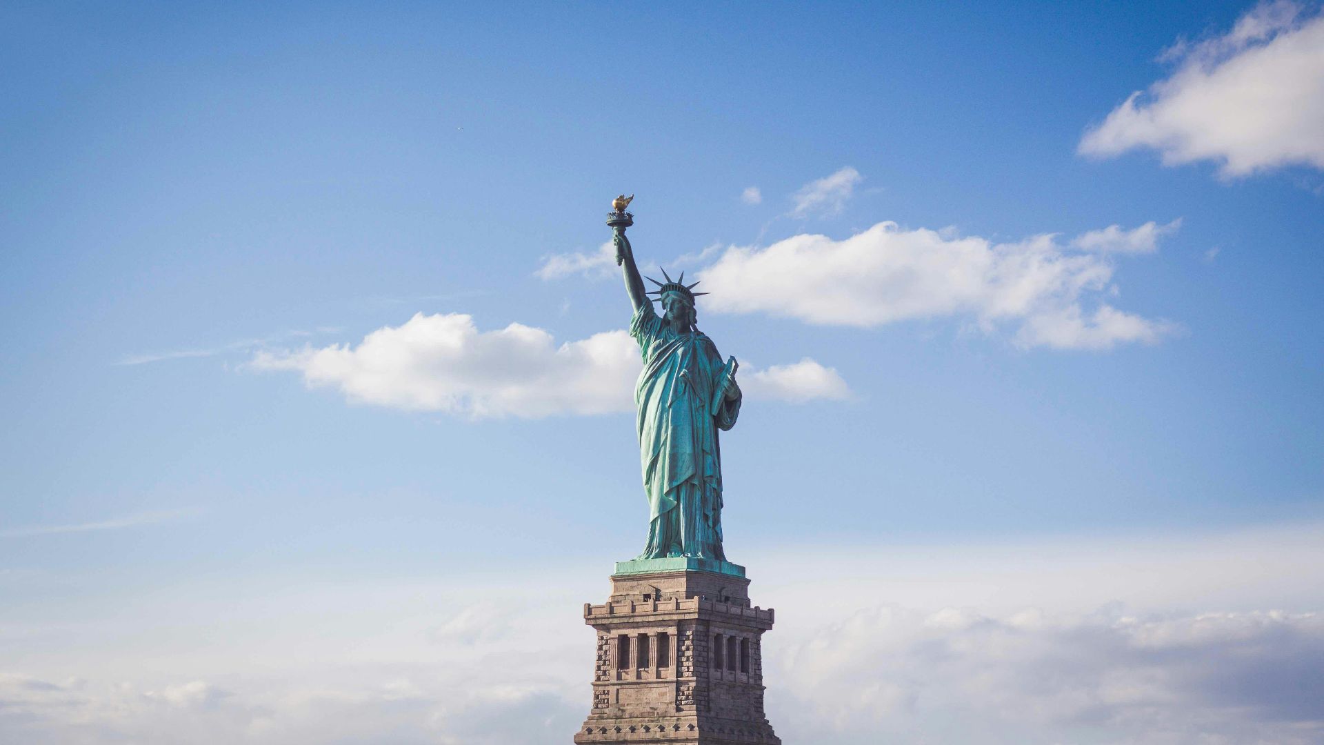 Statue of Liberty, New York under white and blue cloudy skies