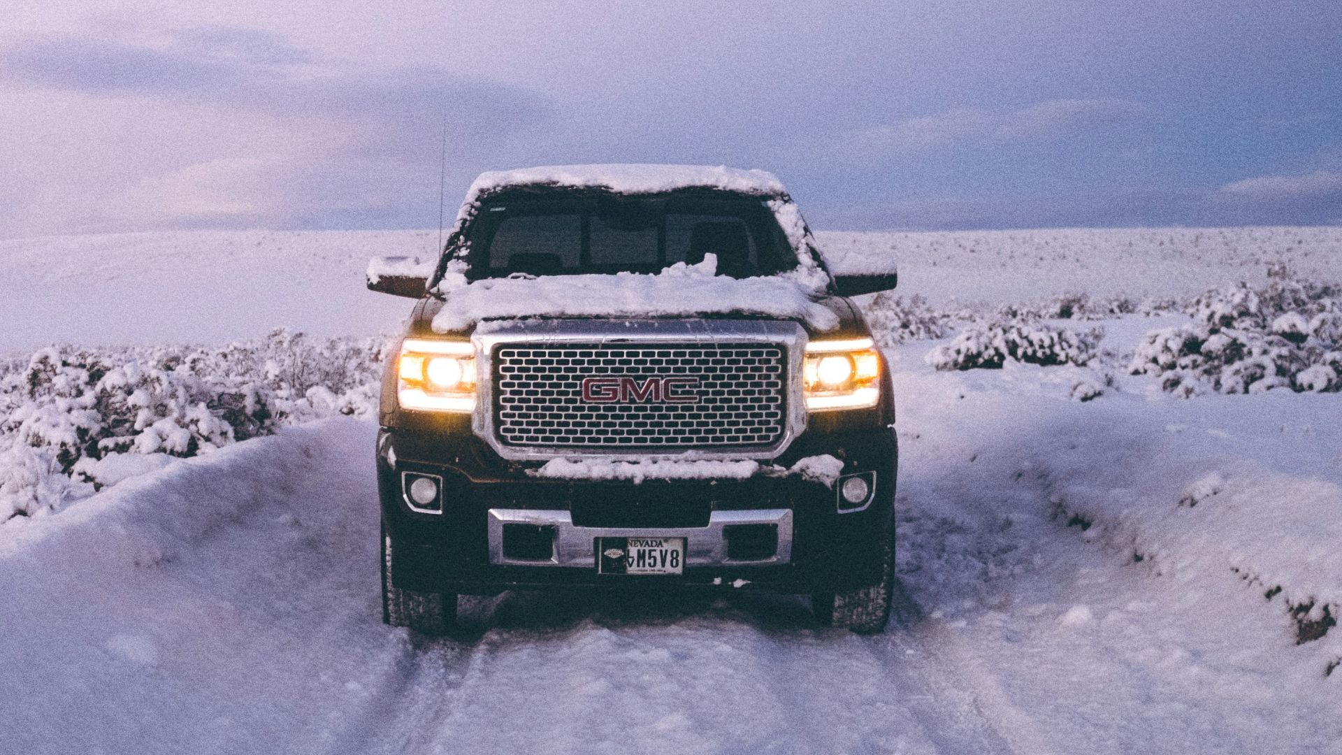 black GMC Sierra Denali on snow covered road