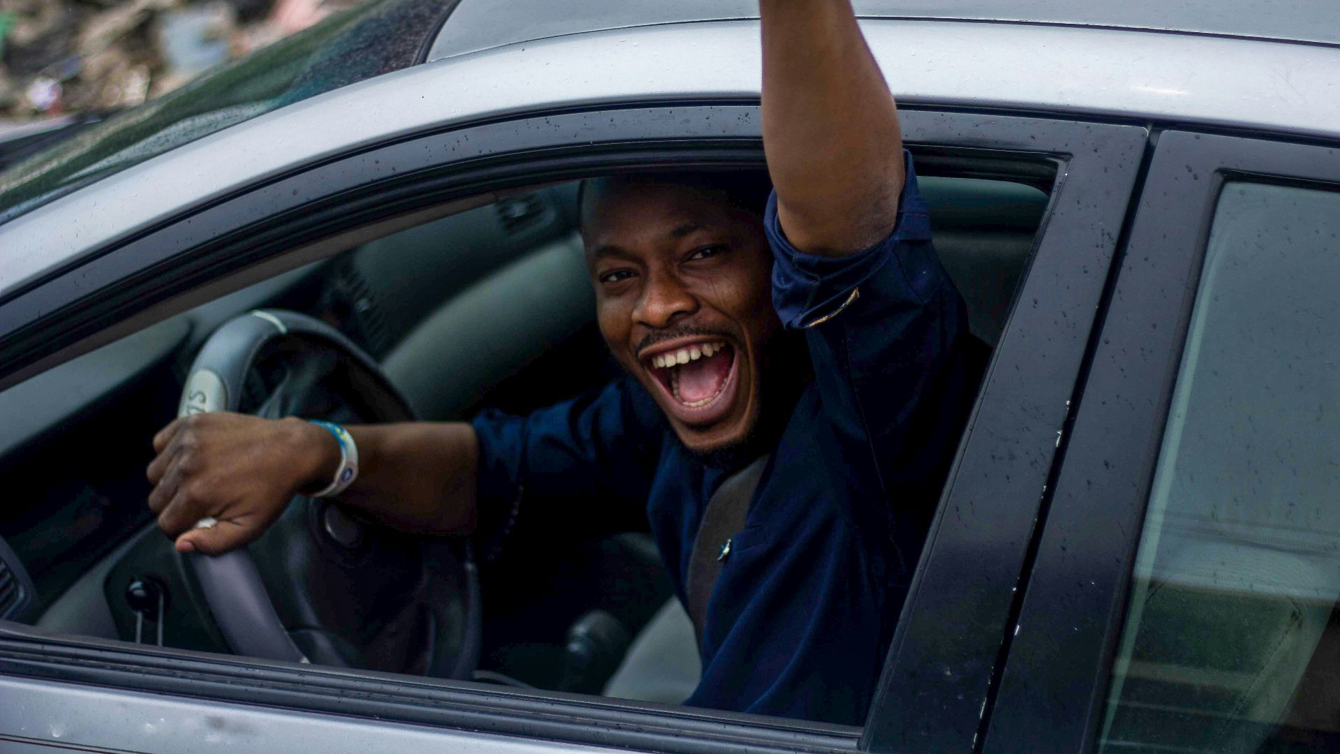 man in black t-shirt and blue denim jeans sitting on car seat