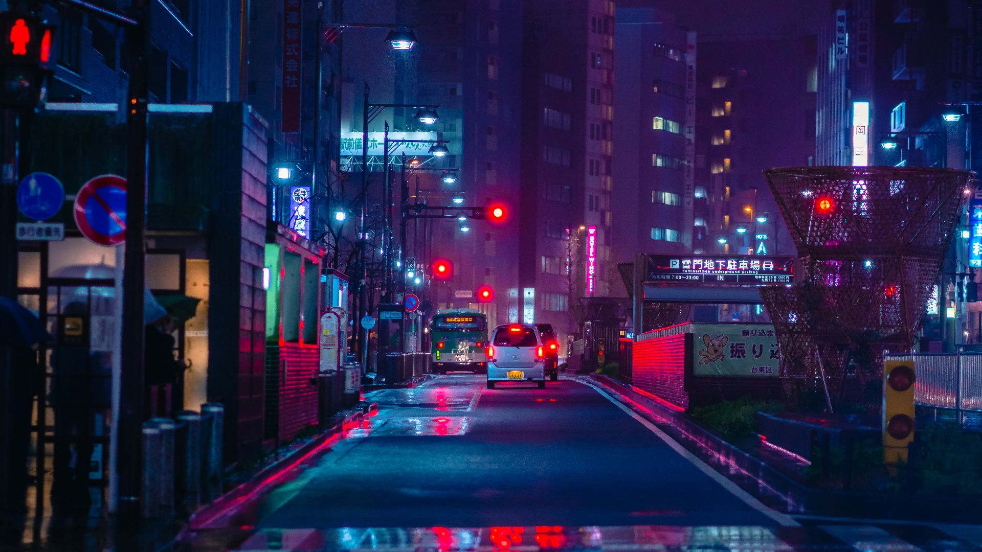 cars on road between high rise buildings during night time