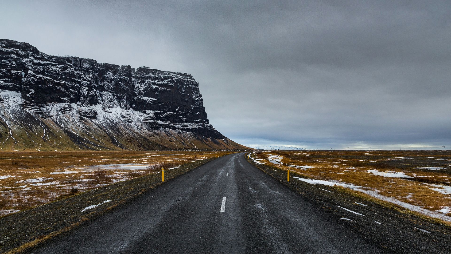 gray asphalt road near gray rocky mountain under gray sky during daytime