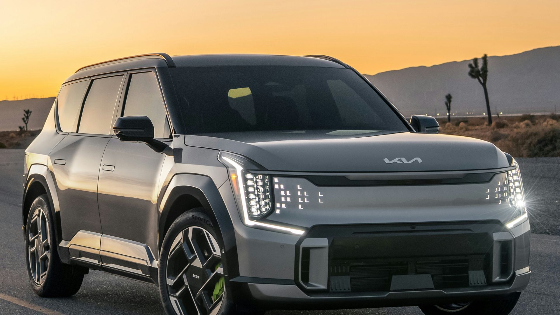 A silver suv driving down a road at sunset