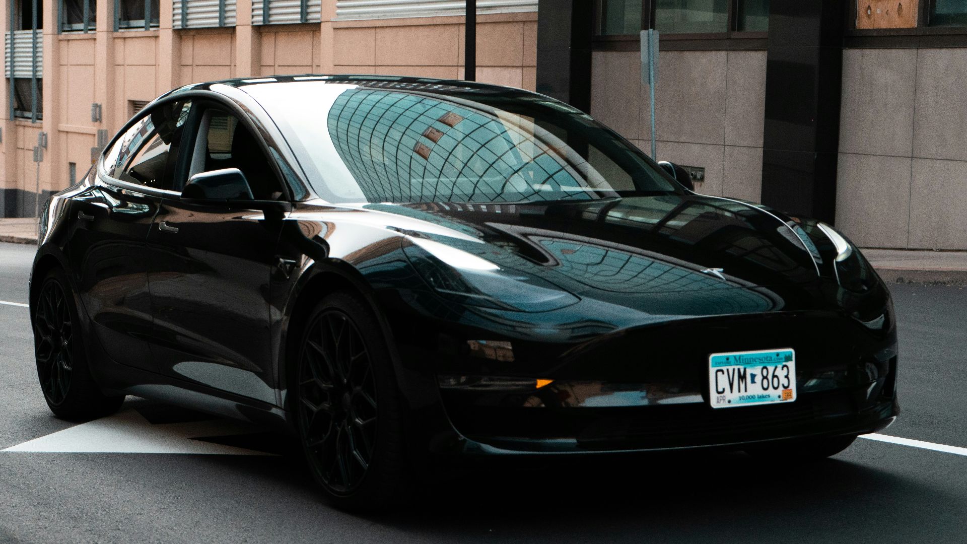a black car driving down a street next to a tall building
