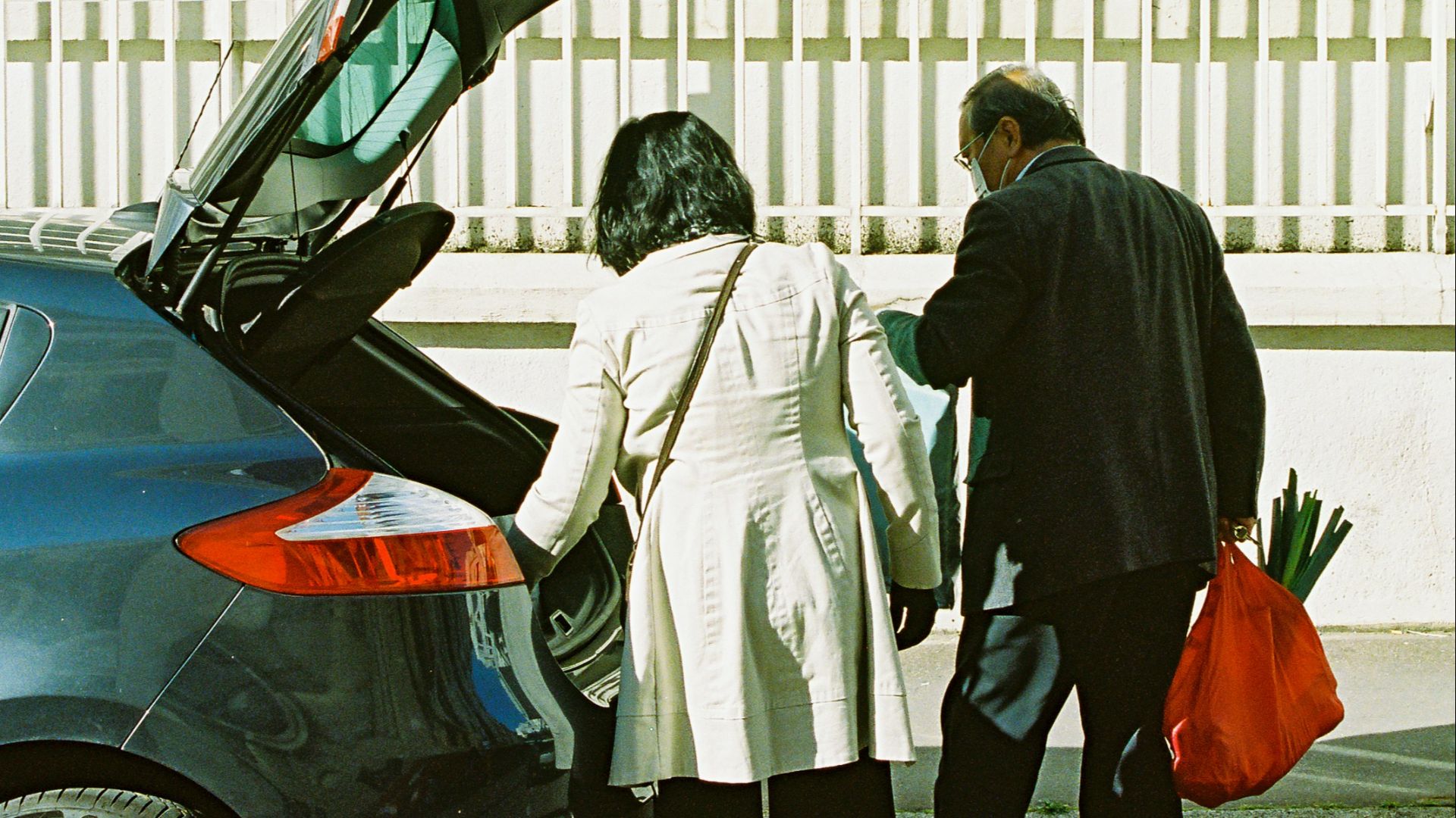 man and woman standing beside black car during daytime