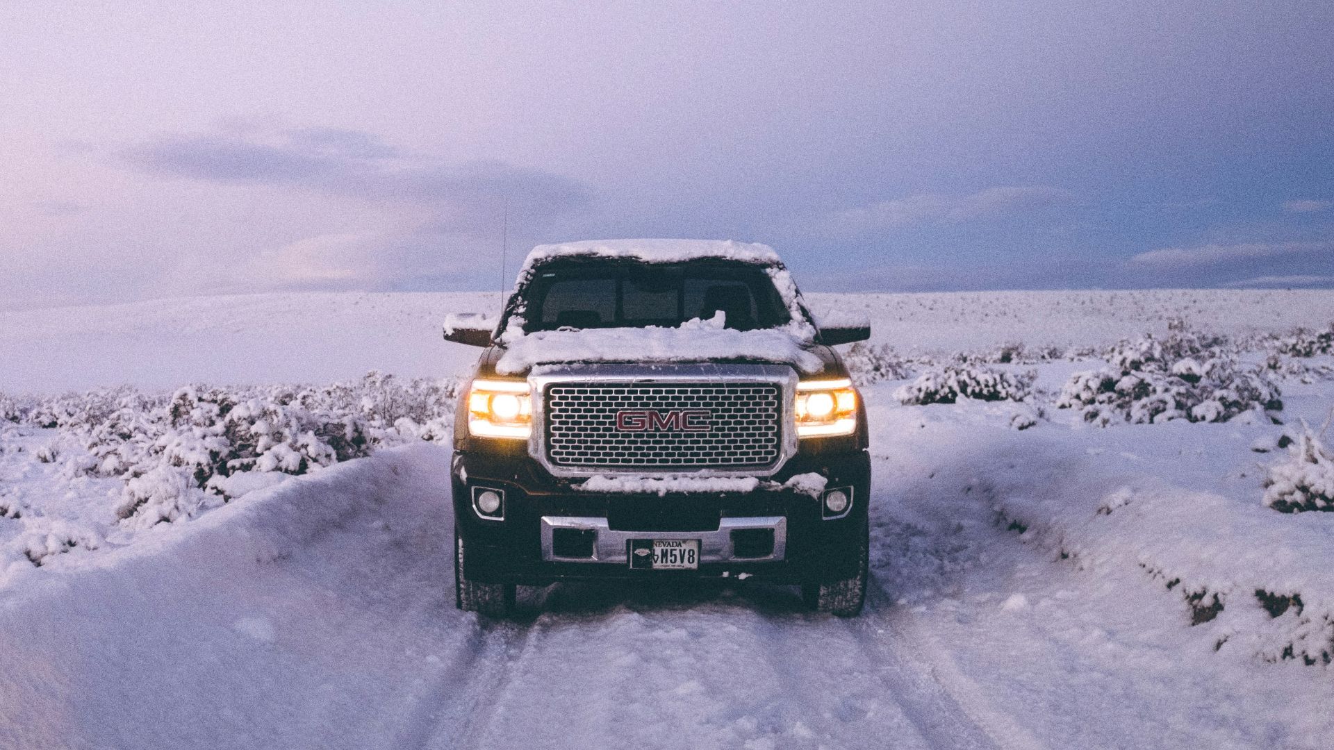 black GMC Sierra Denali on snow covered road
