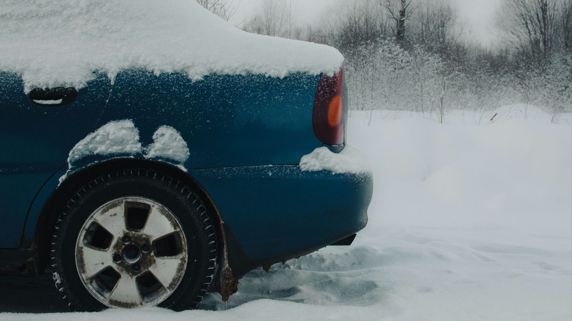 a blue car covered in snow on a snowy day