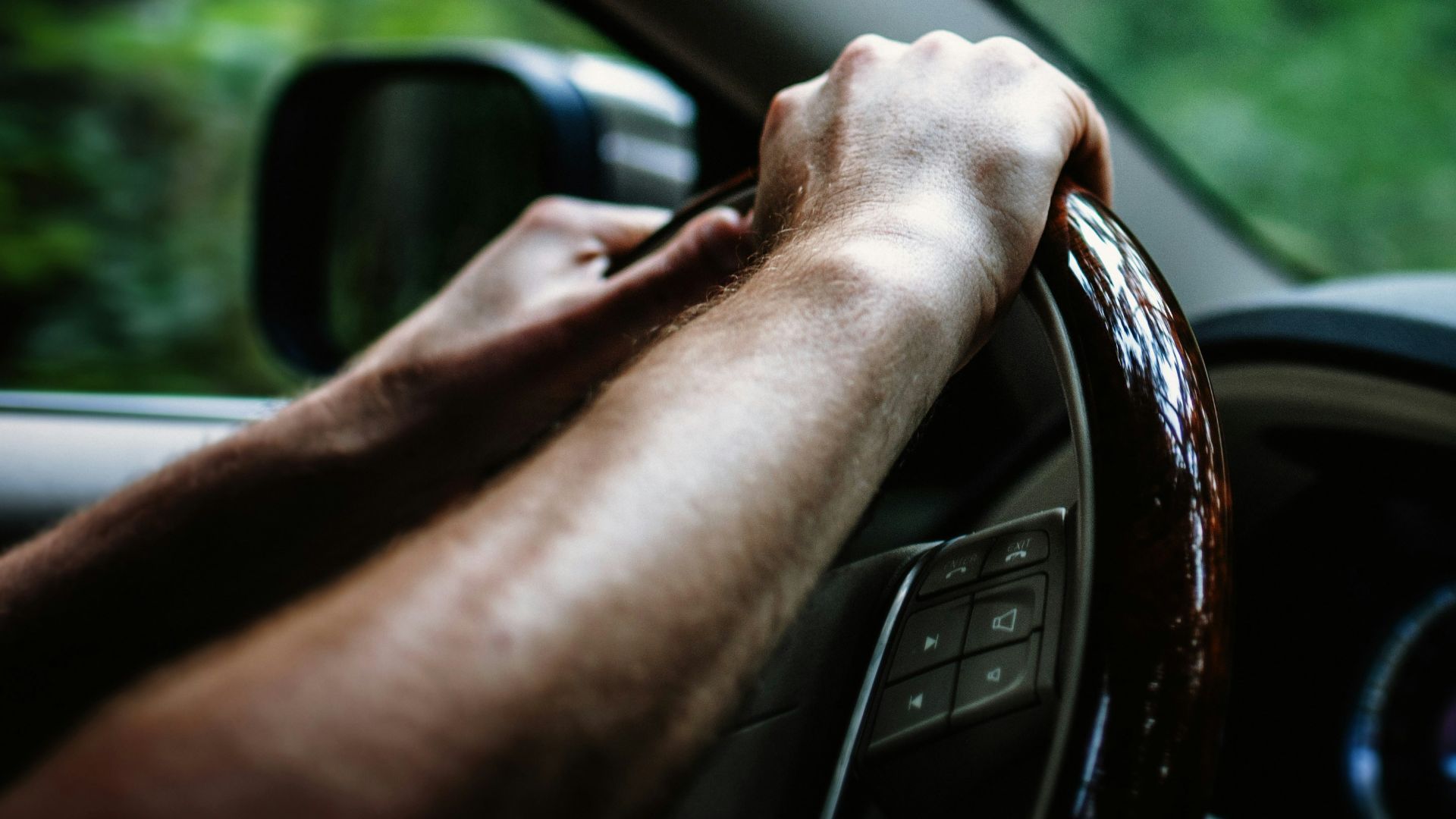 person holding car steering wheel