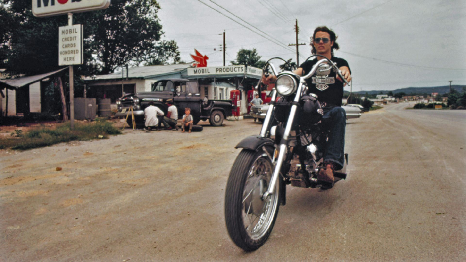 a man riding a motorcycle down a dirt road