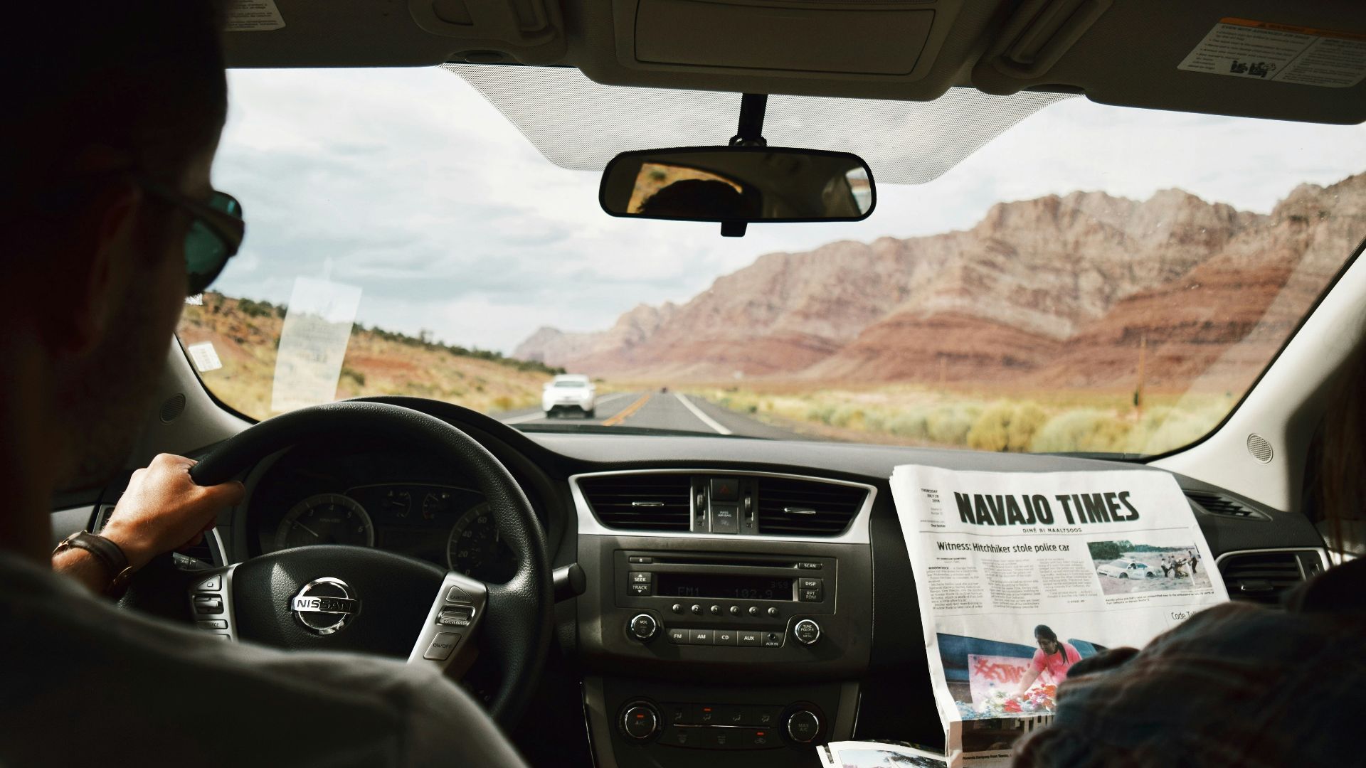 a man driving a car with a newspaper in his hand