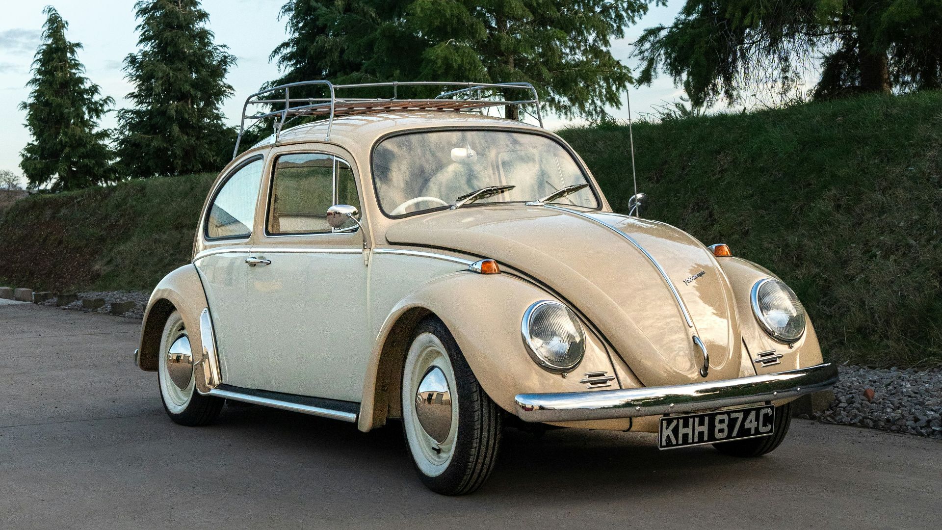 An old vw bug is parked in a parking lot