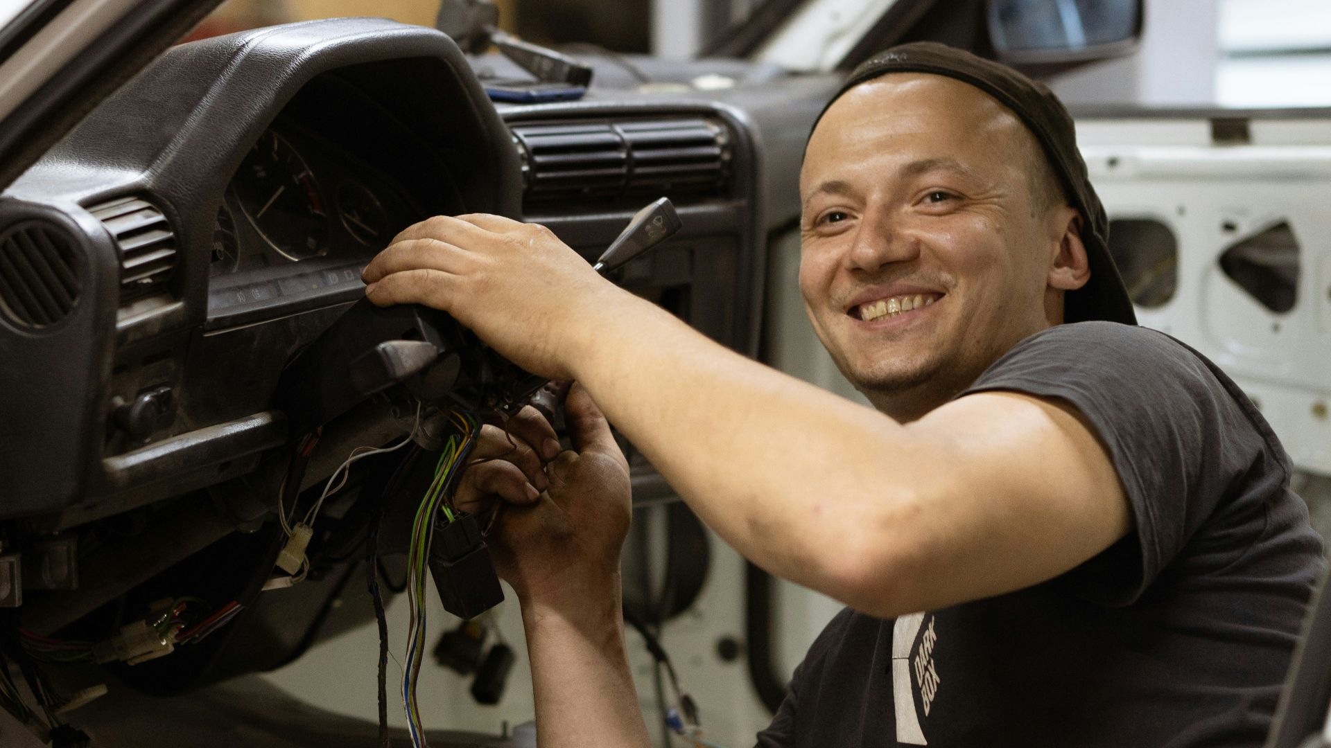 man in black crew neck t-shirt holding black car steering wheel