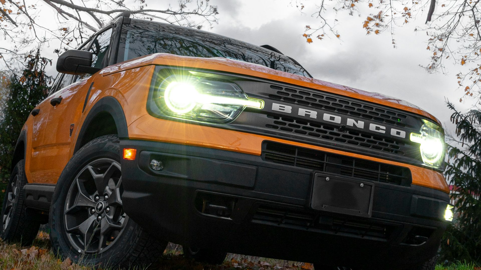 a bright orange truck is parked under a tree