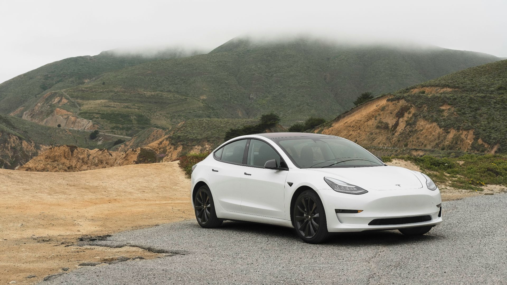 white sedan parked beside mountain during daytime