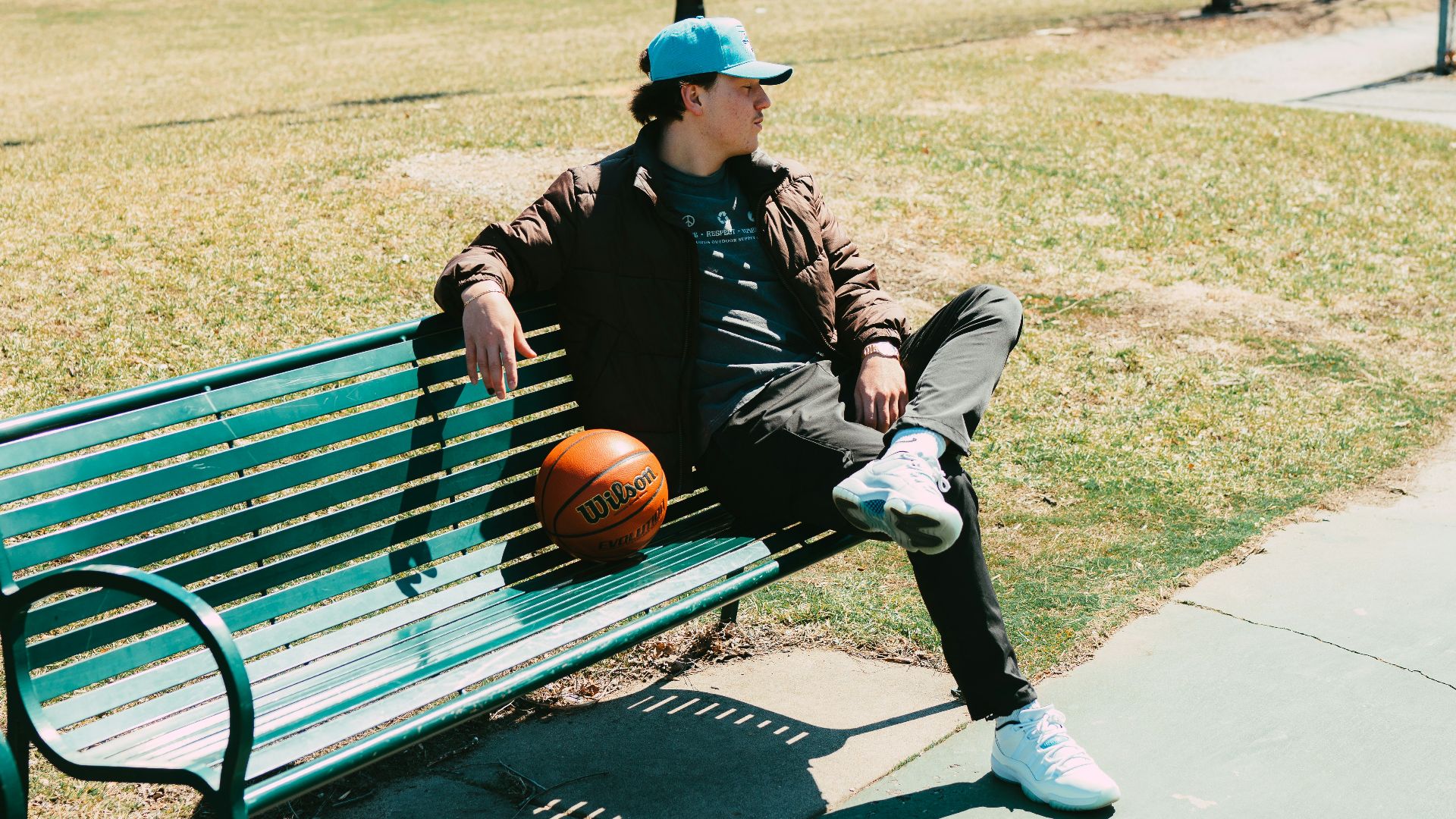 a man sitting on a bench with a basketball in his hand