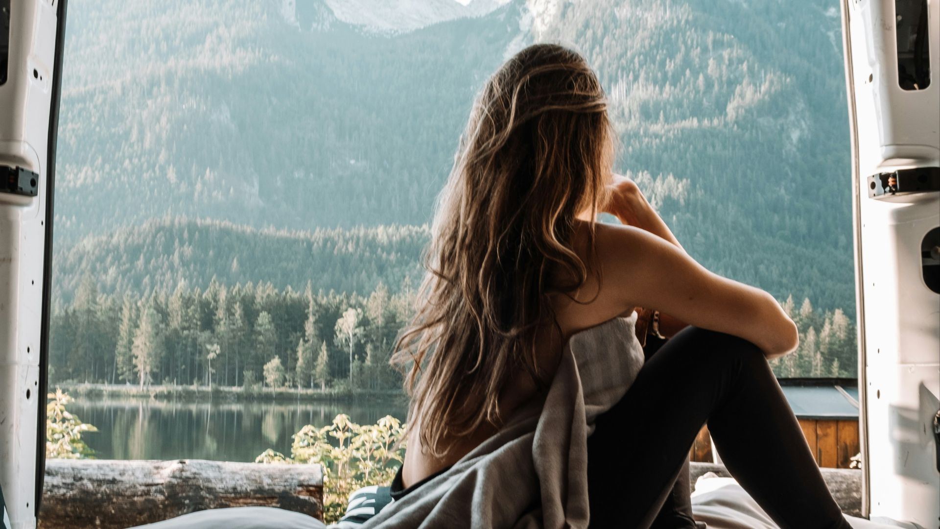 woman in black tank top and black pants sitting on bed