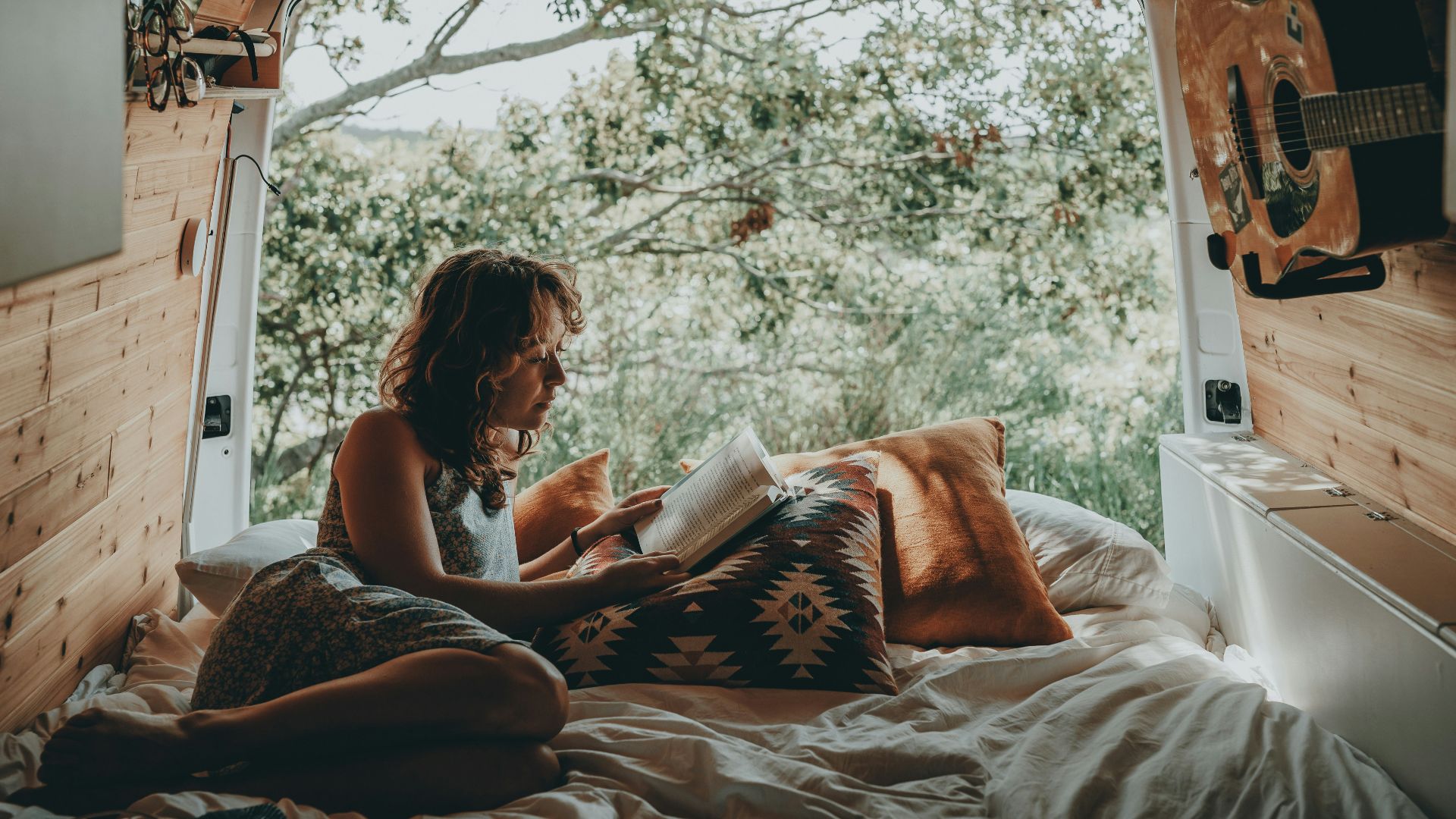 a woman sitting on a bed reading a book