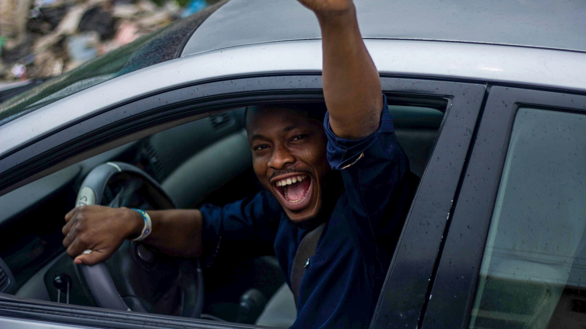 man in black t-shirt and blue denim jeans sitting on car seat