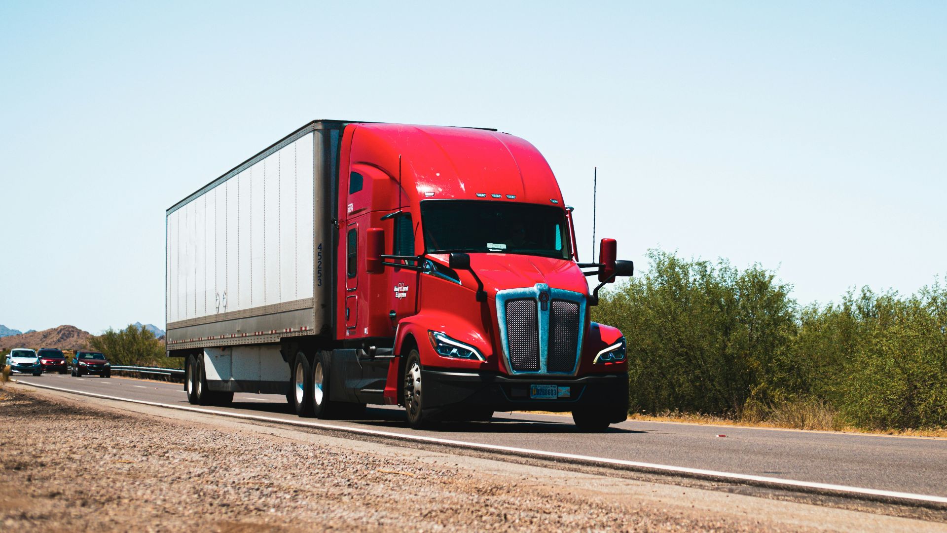 A red semi truck driving down a country road