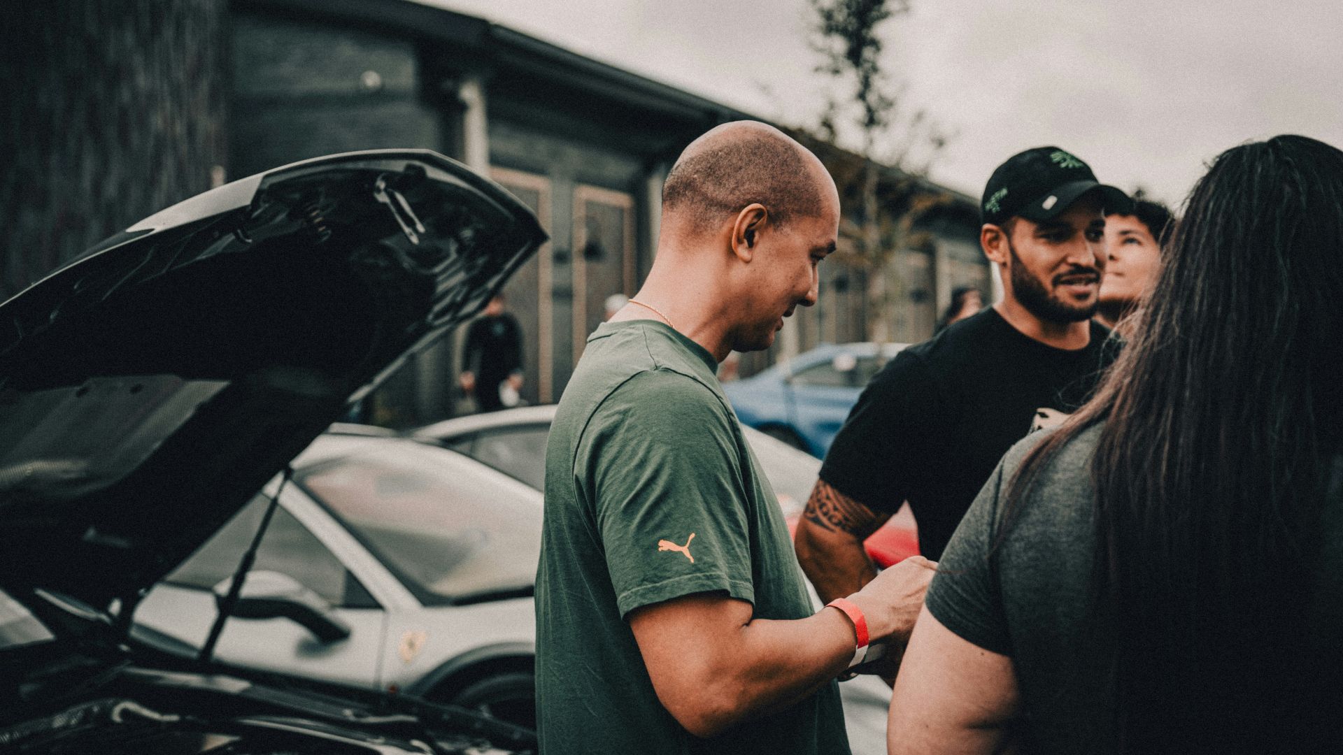 A group of people standing around a parked car