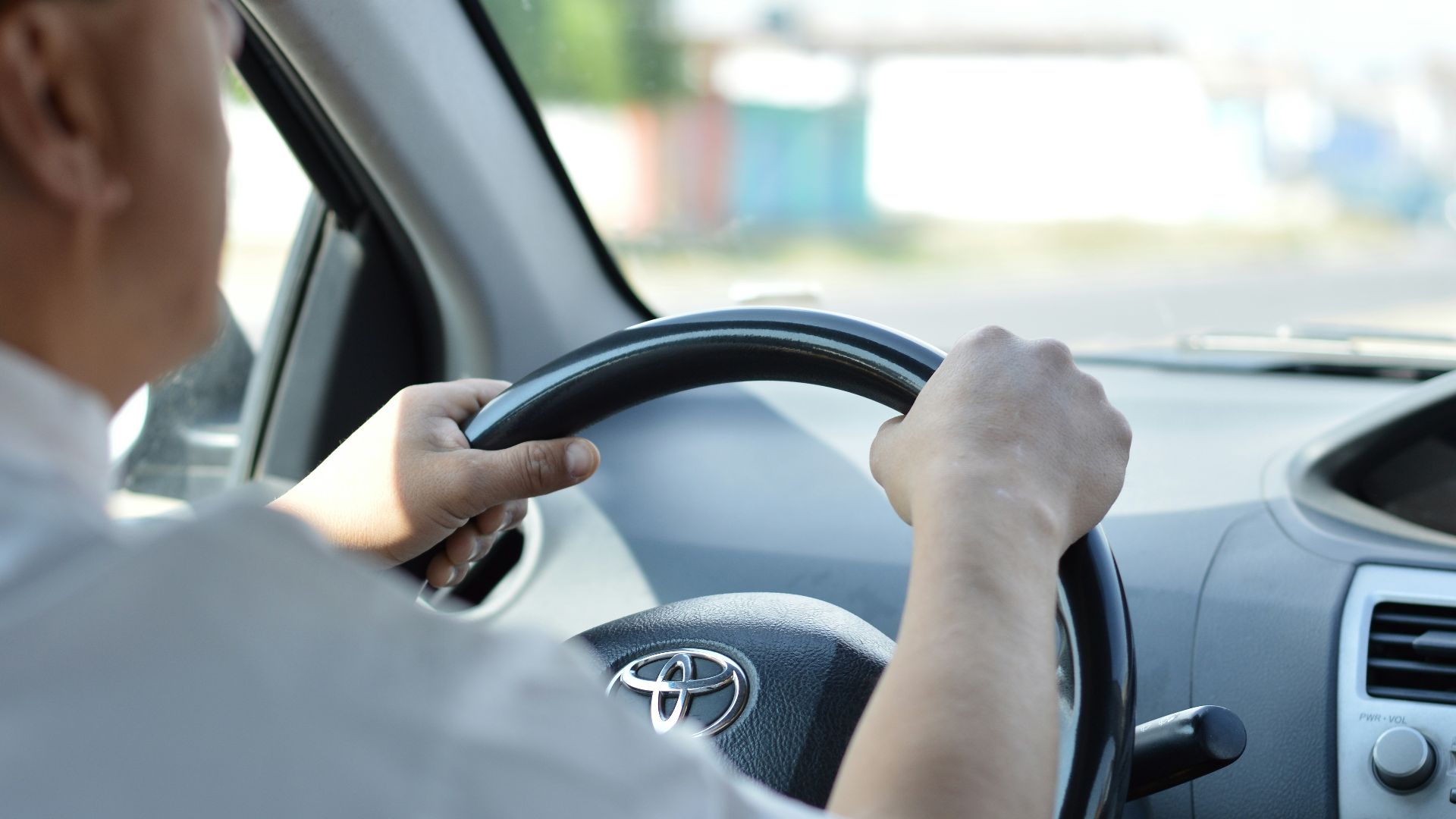 person in white long sleeve shirt driving car