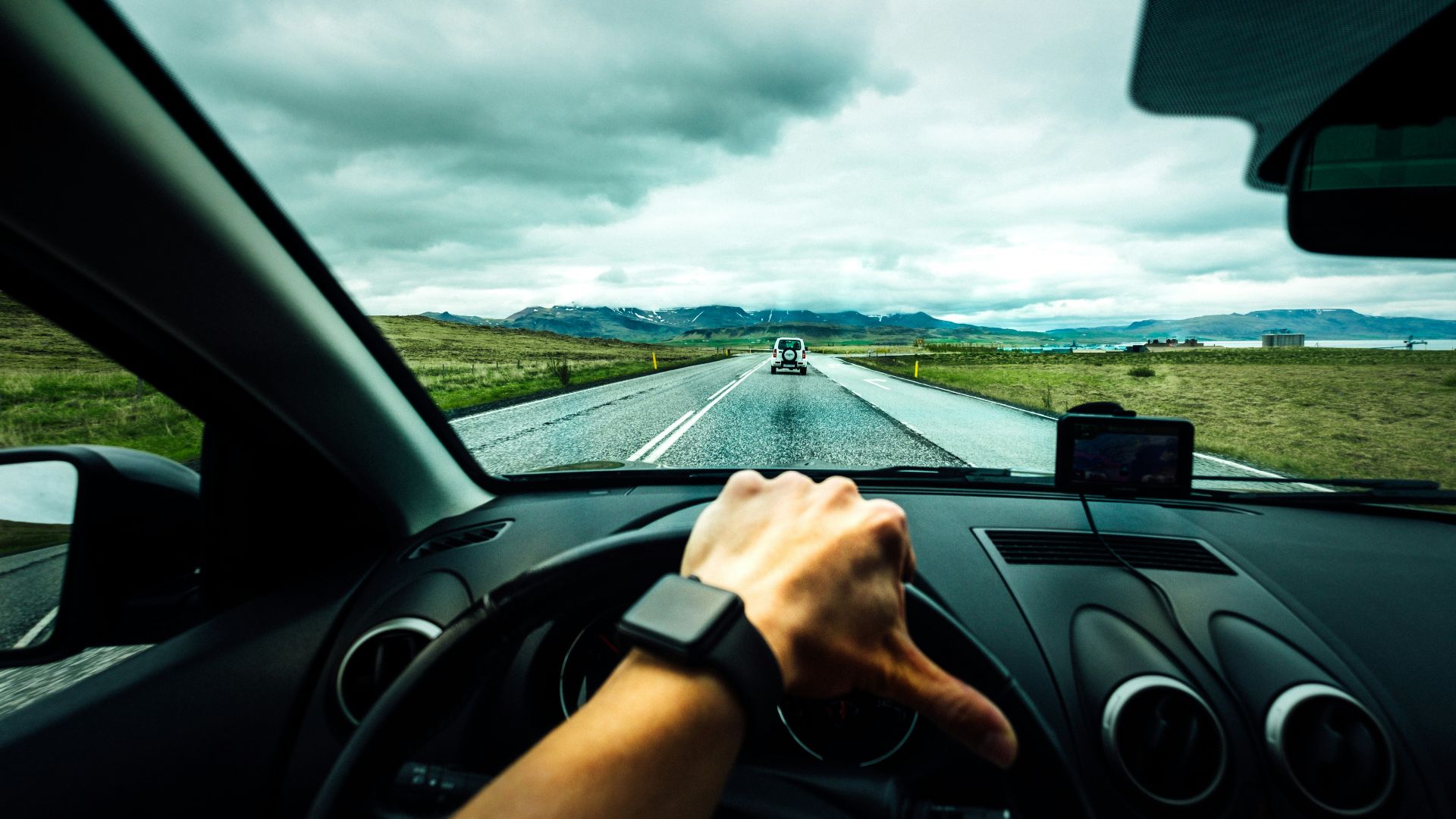 person driving car near vehicle under nimbus cloudes
