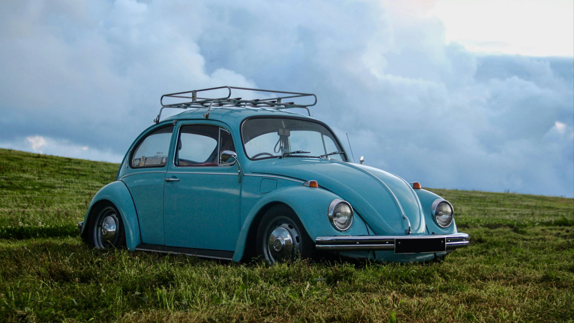 blue Volkswagen Beetle on grass field