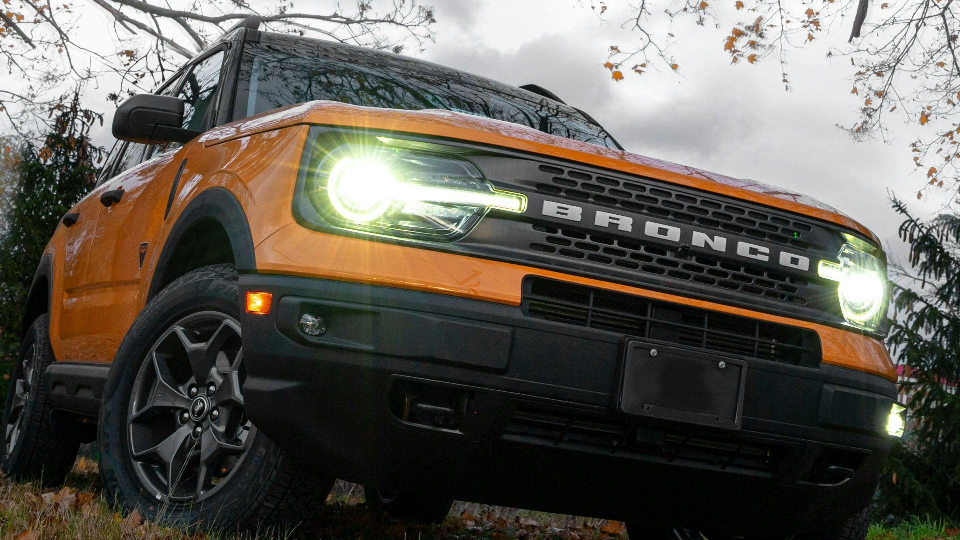 a bright orange truck is parked under a tree