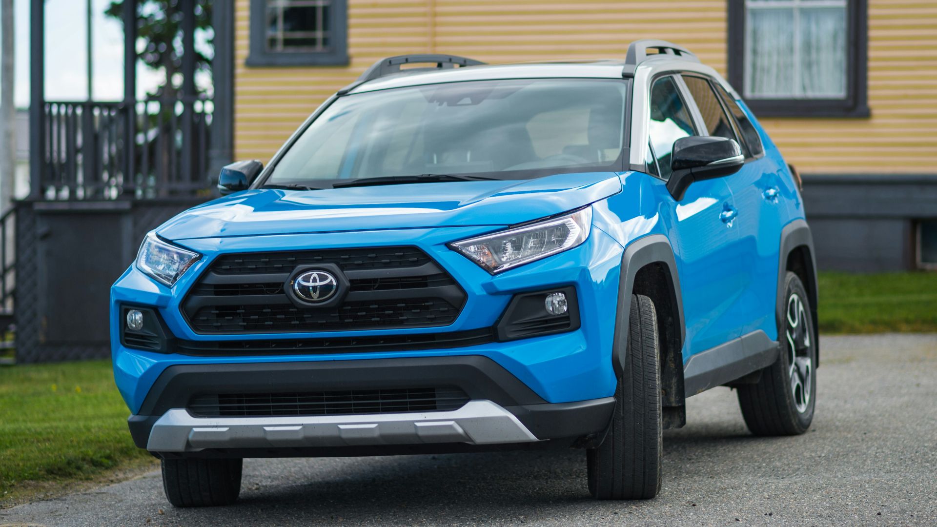 a blue toyota rav parked in front of a house