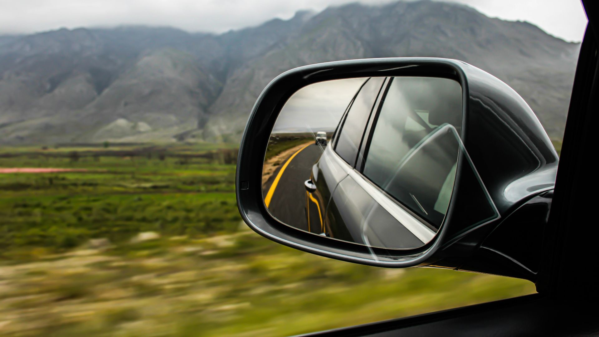 view of vehicle side mirror with vehicle at the back