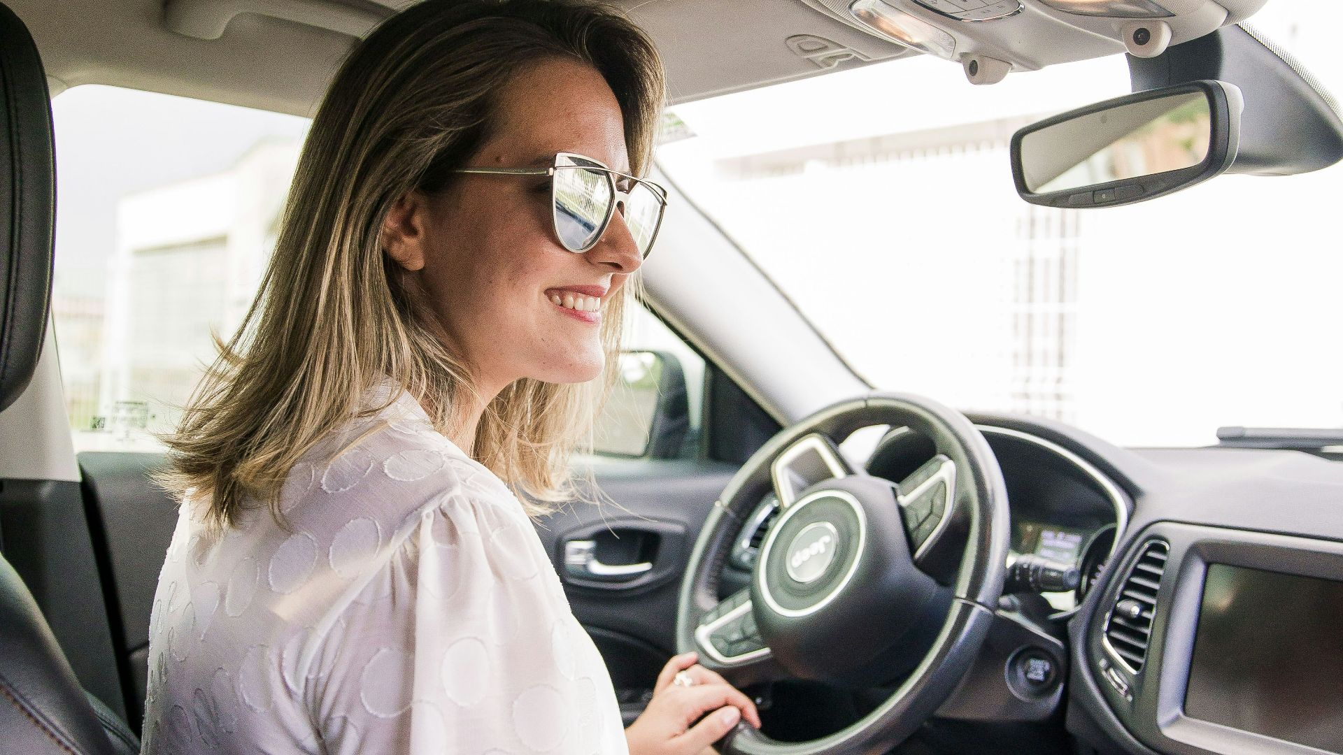 woman in white long sleeve shirt driving car