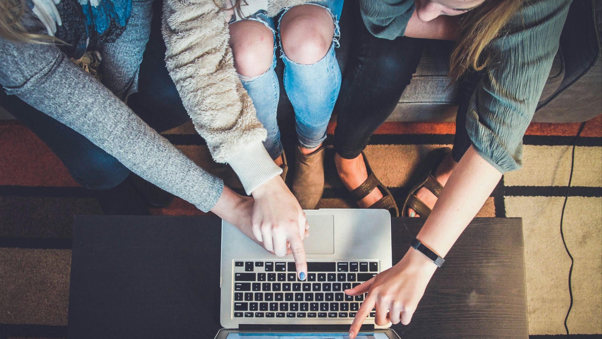 three person pointing the silver laptop computer