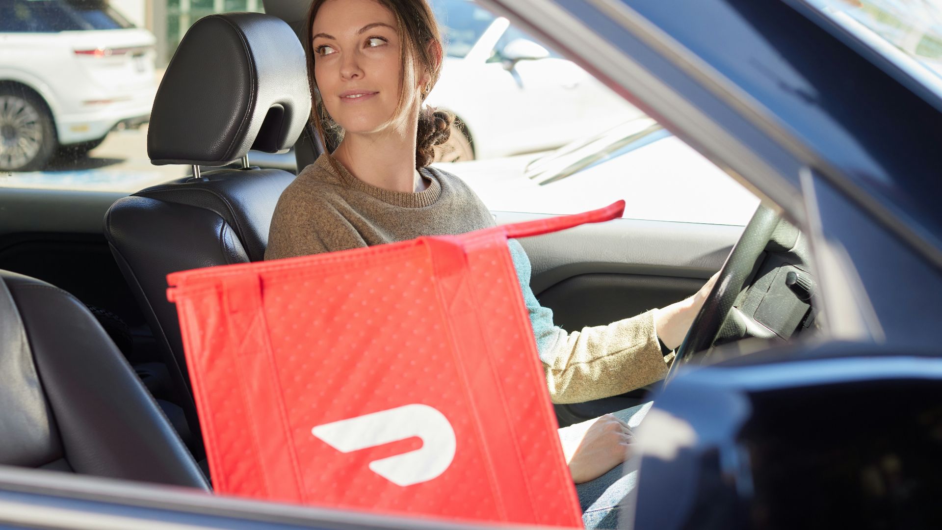 a woman sitting in a car with a shopping bag