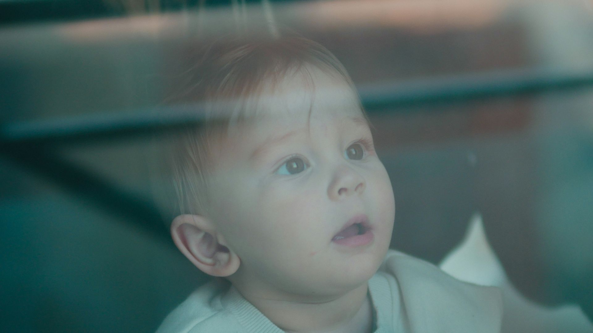 a little boy sitting in a car seat looking out the window