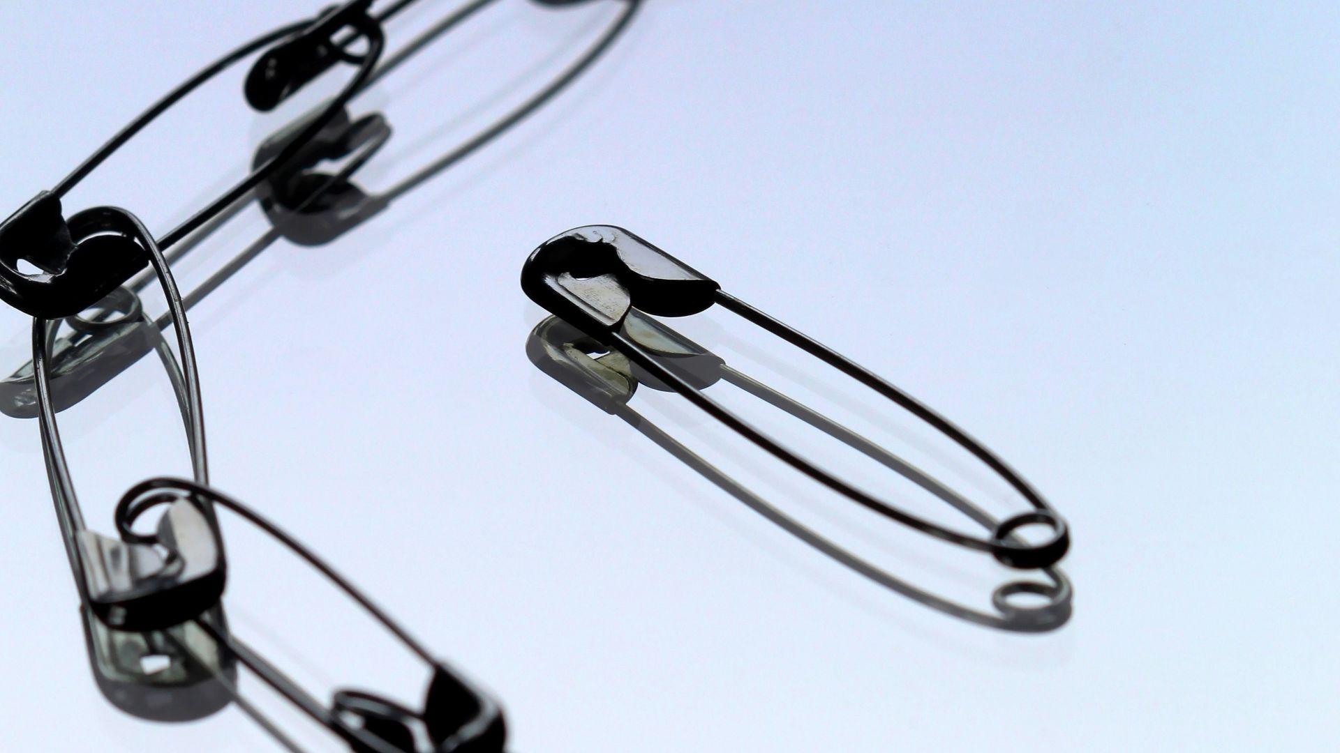 silver safety pin on white paper