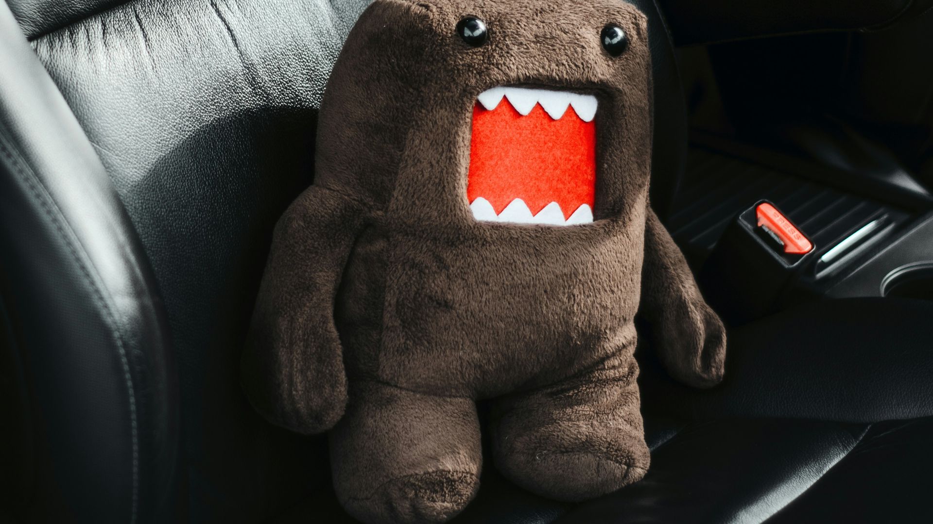Domo plush toy sits in a car seat.